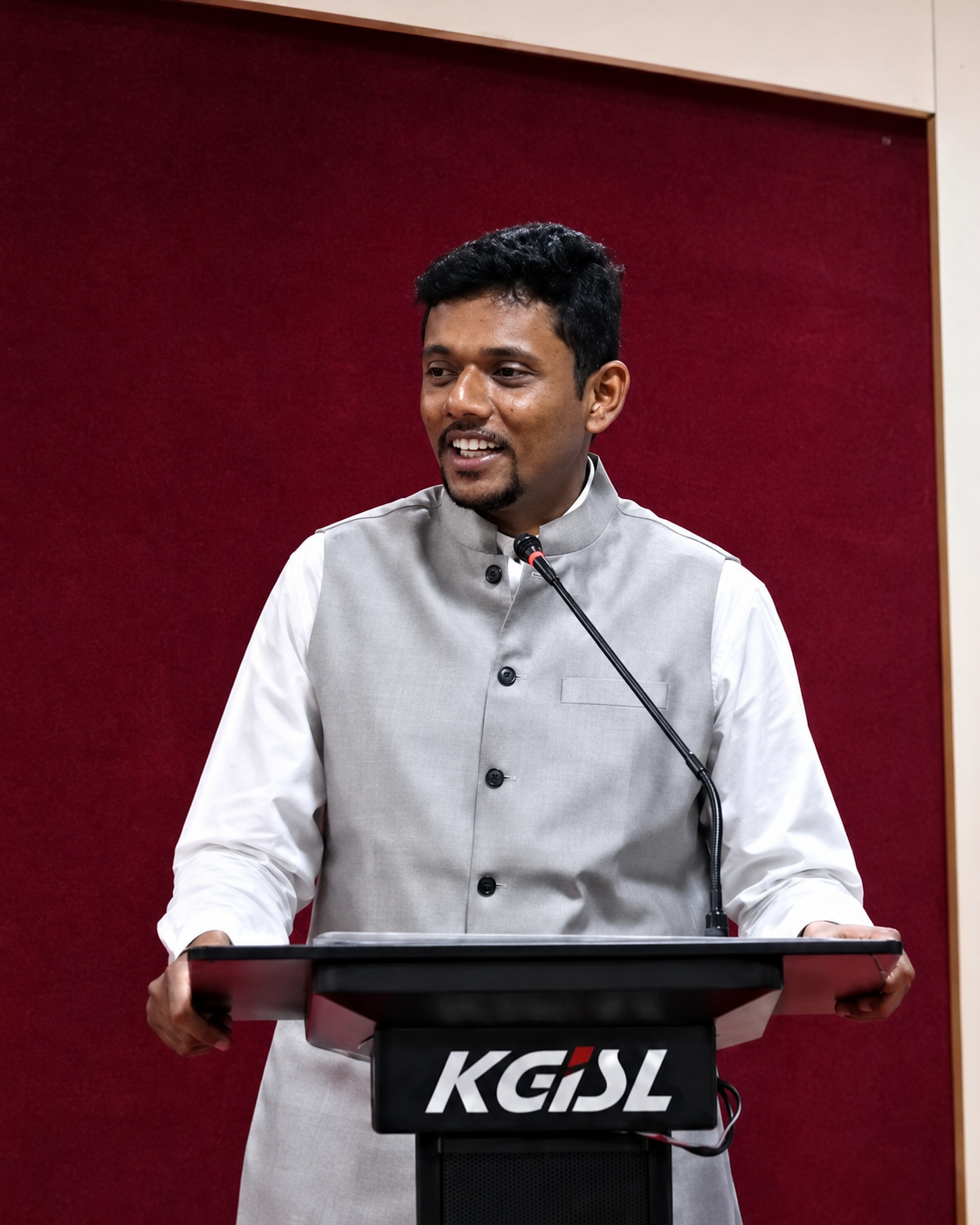 Dr. Ashwin Nithish speaking at a podium at KGiSL, Coimbatore